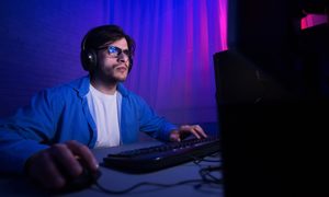 La imagen muestra a un joven jugando frente al computador.