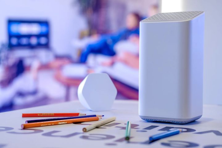 Extensor tipo malla hexagonal xFi Pod Xfinity en una mesa con lápices de colores