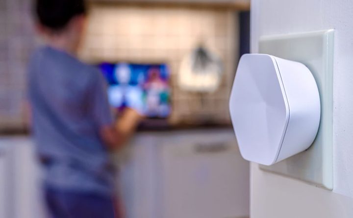 Vista en primer plano de xFi Pod Xfinity y al fondo un niño viendo un televisor