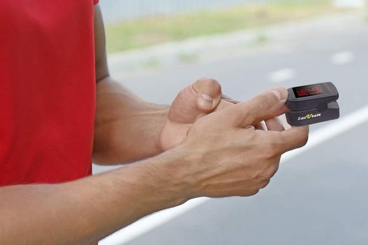 Un hombre con el Zacurate Pro Series 500DL Fingertip Pulse Oximeter en mano, el mejor para tomarte el pulso