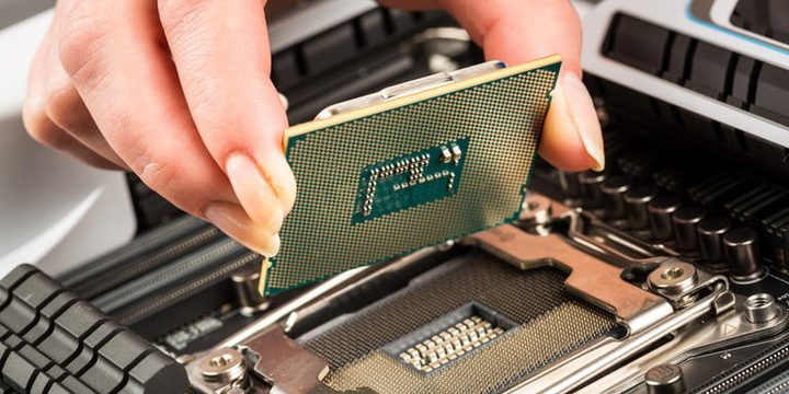 Una persona con un procesador en la mano para instalarlo en una placa base y comparar Intel i5-10600K vs. i7-10700K