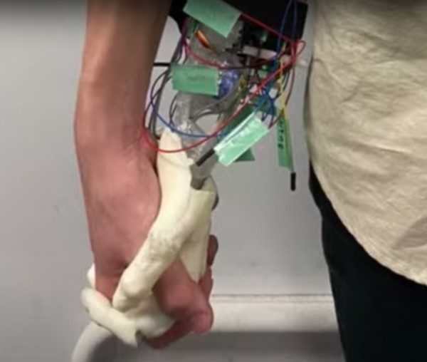 La imagen muestra un brazo robótico que recrea la sensación de caminar tomados de la mano.