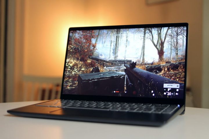 Laptop con imagen de un juego que muestra un rifle en un bosque