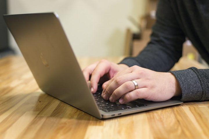 Una persona usando una MacBook Air sobre un escritorio de madera para la comparativa de Apple vs. Microsoft