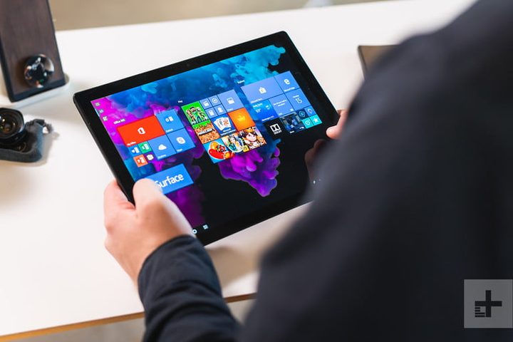 Una persona usando una Surface para comparar Apple vs. Microsoft