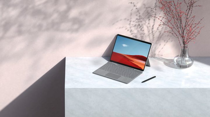 Surface Pro sobre una mesa blanca junto a un florero para comparativo entre Apple M1 MacBooks vs. Microsoft Surface Pro X