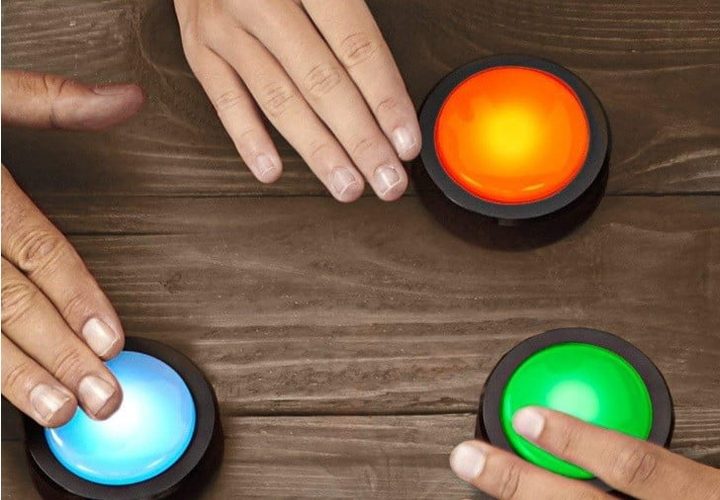 Las manos de unas personas jugando con los Botones Echo para comparar Google Home vs. Amazon Echo