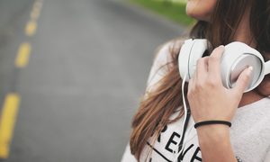 La imagen muestra a una mujer con audífonos.