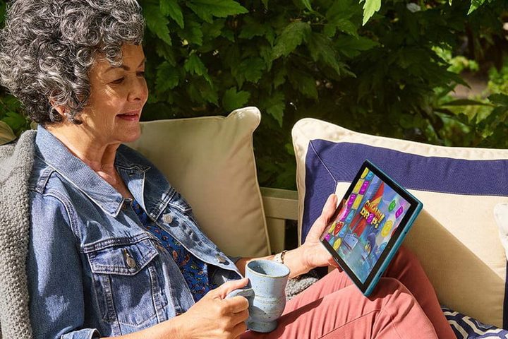 Señora sentada en un jardín con tableta en la mano para mostrar una de las las mejores tablets baratas