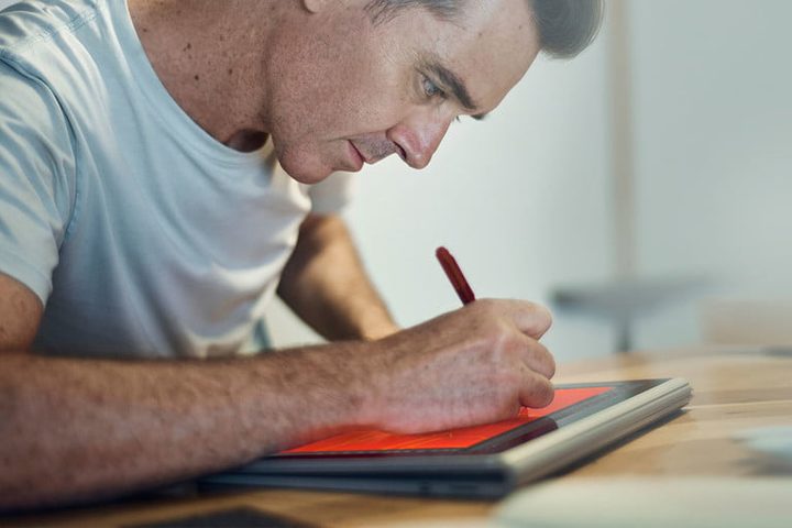 Un hombre con su laptop investigando cuánto cuesta Microsoft Office