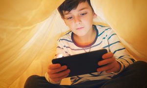 La imagen muestra a un niño mientras juega con su teléfono celular.
