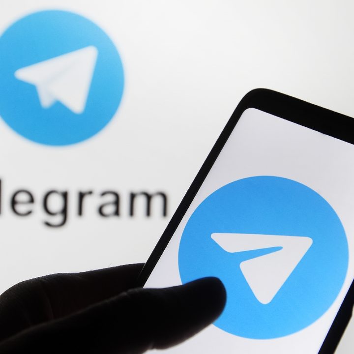 Un teléfono con el logo de Telegram de fondo