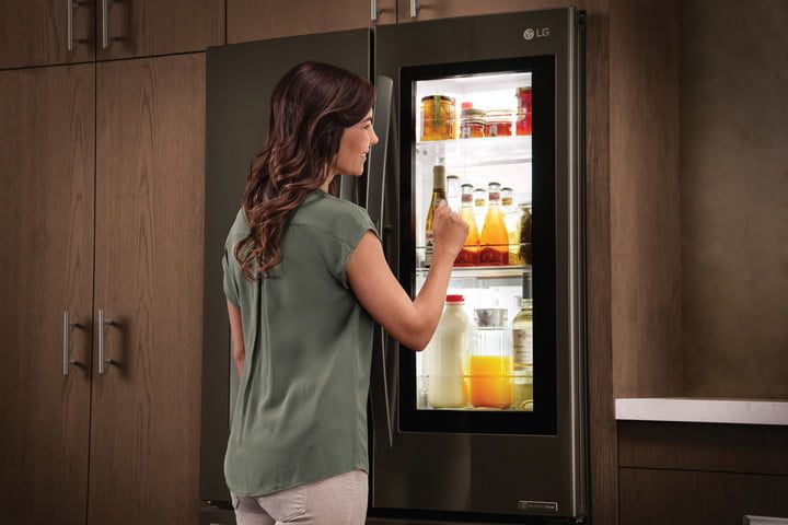 Una mujer viendo a través de la ventana de un refrigerador LG, una de las mejores marcas de frigoríficos más fiables