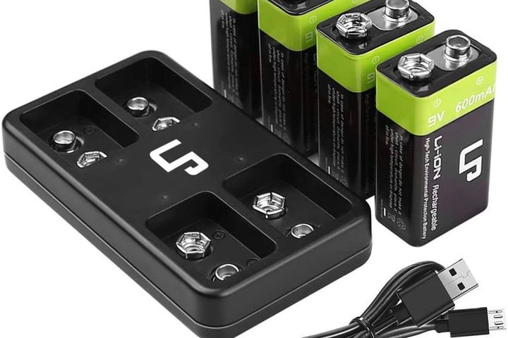 Cuatro pilas LP negras con verde de 9 V junto a un cargador