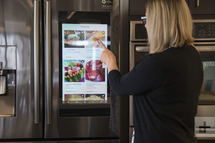 Una mujer usando la pantalla de su refrigerador Samsung, , una de las mejores marcas de frigoríficos más fiables
