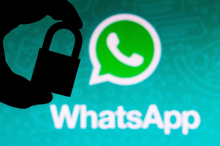 Una persona sostiene un candado con el logo de WhatsApp de fondo