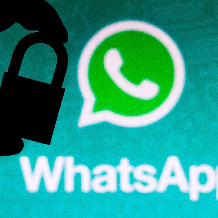 Una persona sostiene un candado con el logo de WhatsApp de fondo