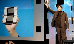 Una fotografía del expresidente de Nintendo, Satoru Iwata, mostrando la consola portátil DS en la expo E3 de 2004