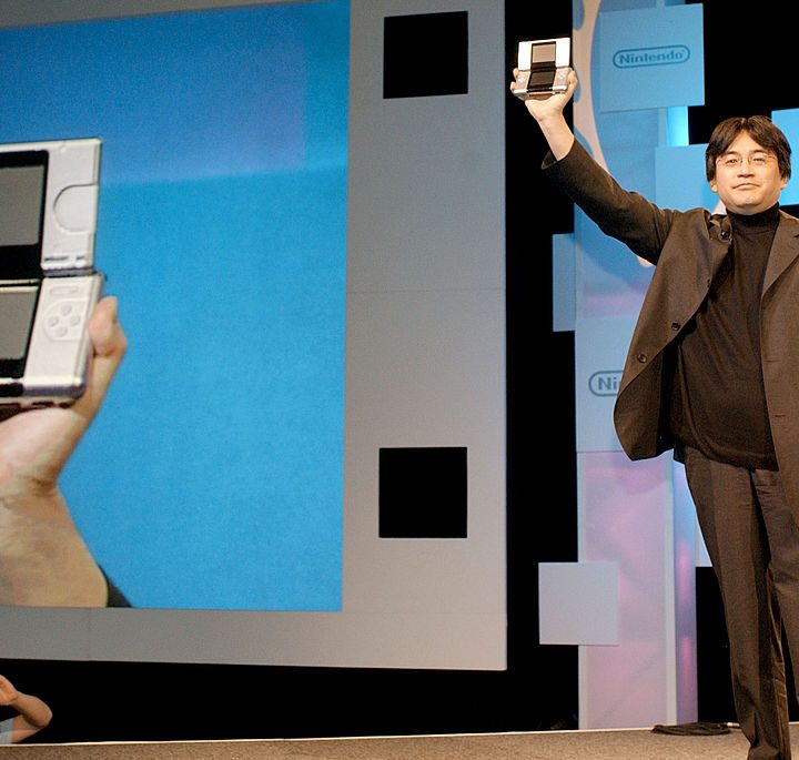 Una fotografía del expresidente de Nintendo, Satoru Iwata, mostrando la consola portátil DS en la expo E3 de 2004