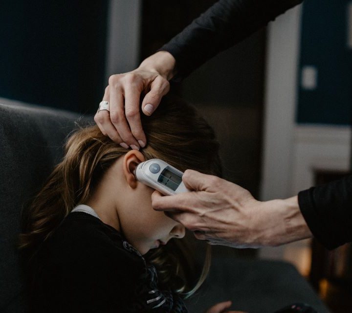 Una persona tomando la temperatura a una niña con uno de los mejores termómetros inteligentes