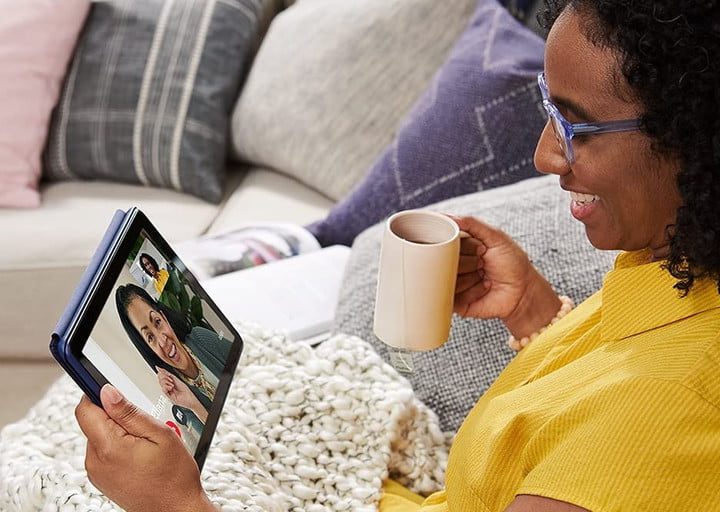 Una mujer sentada en un sofá usando una tableta en una videollamada