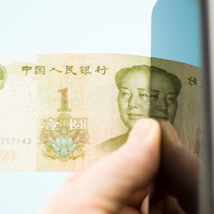 Una persona sostiene un yuan junto a un teléfono