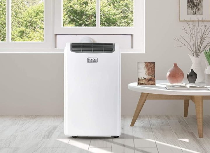 Aparato portátil en una habitación junto a una mesa de centro, para aprender a cómo instalar un aire acondicionado portátil