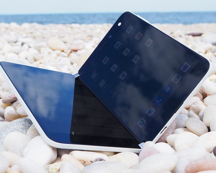 Surface Duo parcialmente abierto en una playa sobre un piso de rocas