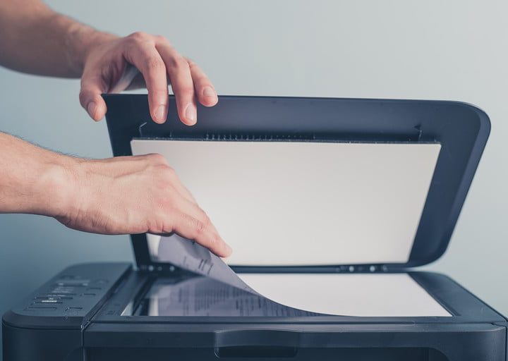 Las manos de una persona volteando una hoja para escanearla a doble cara