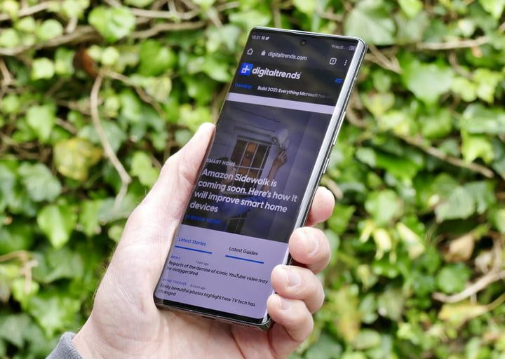 Celular en la mano de una persona con un jardín al fondo para comparar al ZTE Axon 30 Ultra vs. Google Pixel 5