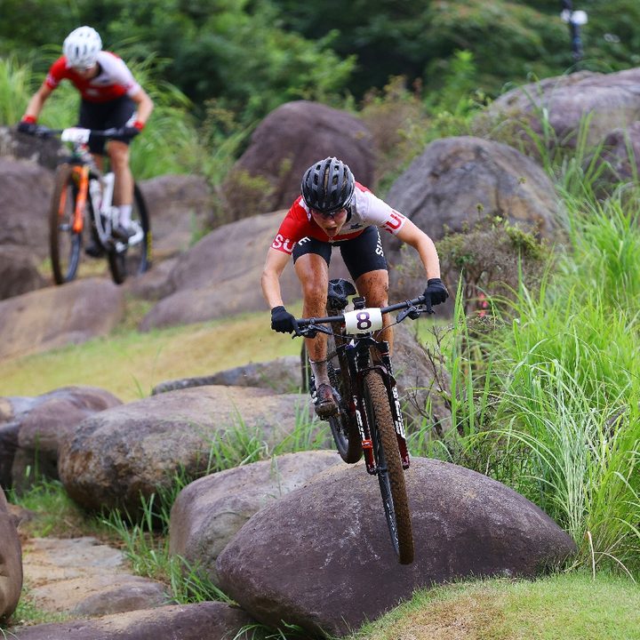 La corredora suiza Sina Frei salta en una roca durante la carrera de cross-country femenino de bicicleta de montaña en Tokyo 2020. Frei se quedó con la medalla de plata.