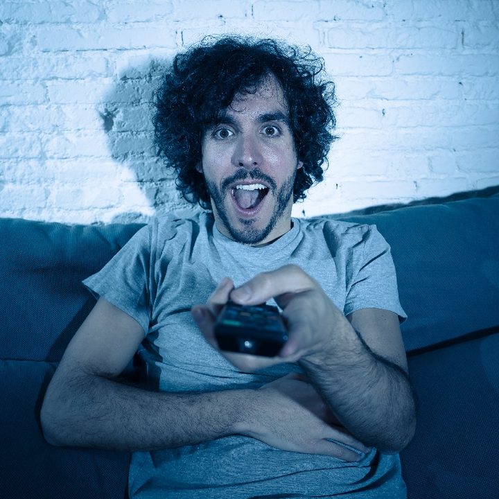 Un hombre con cara de sorpresa y un control remoto en la mano