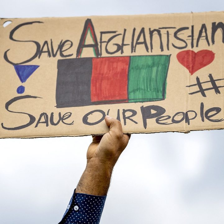 Una persona sostiene un letrero que pide ayuda para Afganistán