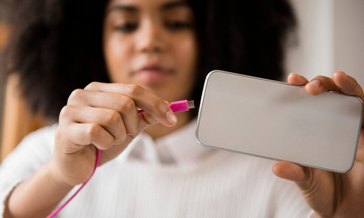 Una persona conecta su teléfono a un cargador