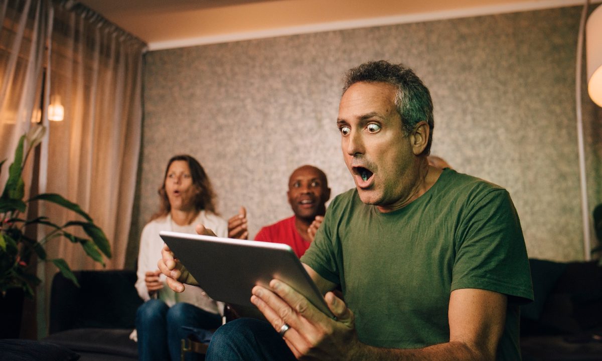 Un hombre mira su tableta con cara de sorpresa