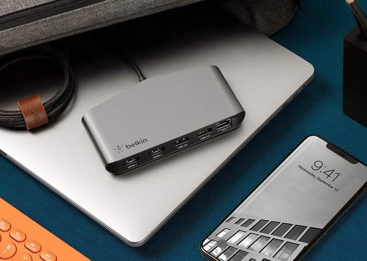 Belkin Thunderbolt 3 Dock Mini sentado en una computadora portátil junto a un estuche de viaje.