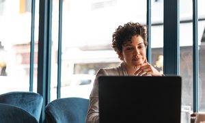 La imagen muestra a una mujer frente a su computadora en la oficina.