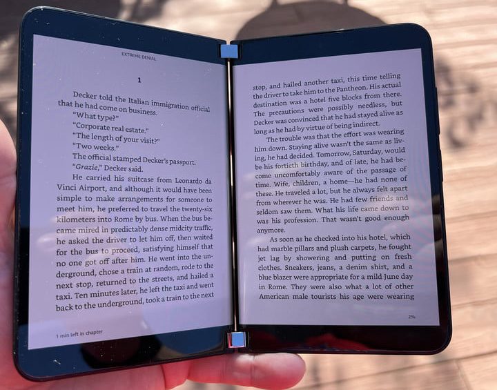 Una mujer recostada usando un celular plegable para comparar al Microsoft Surface Duo 2 vs. Samsung Galaxy Z Fold 3.