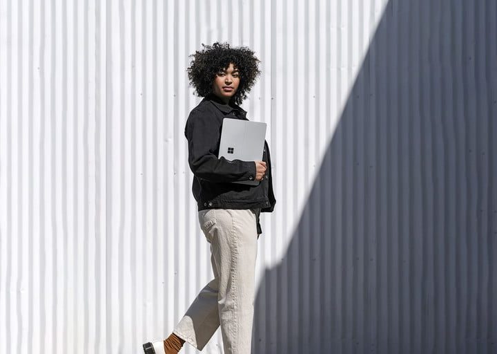 Mujer caminando con Surface Laptop Studio en mano.