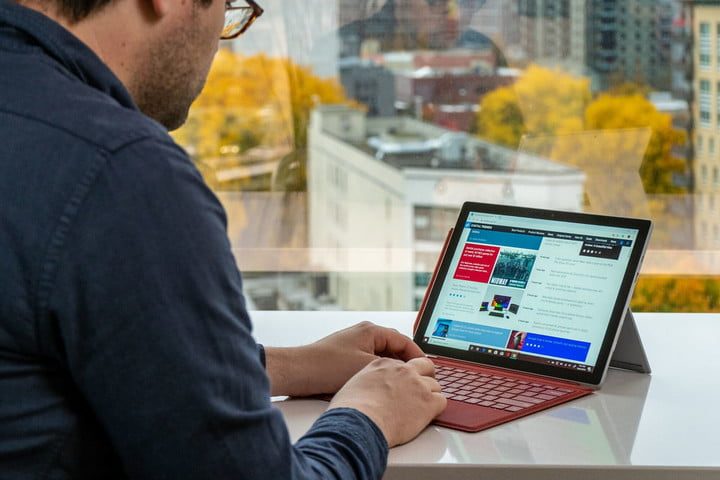 Una persona escribe en un Surface Pro 7 con una funda con teclado roja.