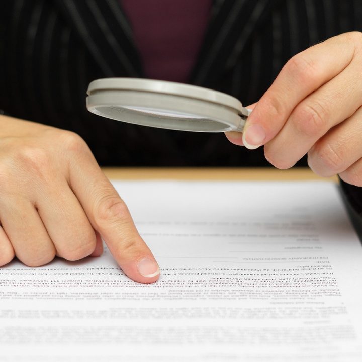 Una persona lee un contrato con una lupa