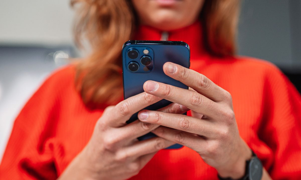 Una mujer sostiene en sus manos un iPhone mientras bloquea una llamada o envía un mensaje de texto.