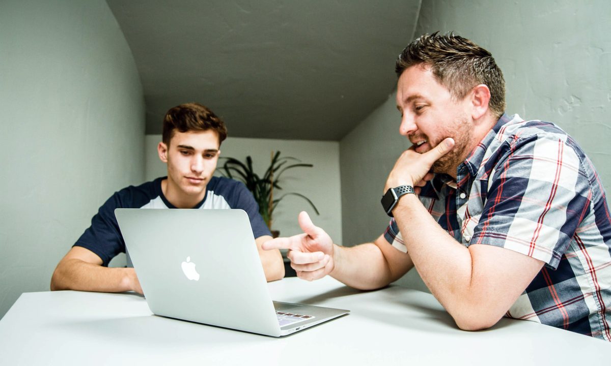 Un hombre explicándole a un amigo cómo grabar un video en Mac