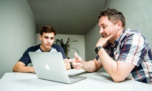 Un hombre explicándole a un amigo cómo grabar un video en Mac