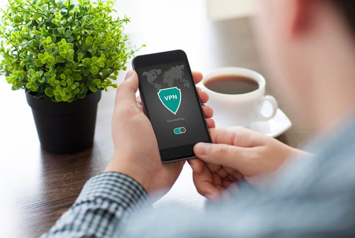 Hombre que sostiene el teléfono con una de las mejores VPN legales para navegar de forma anónima.