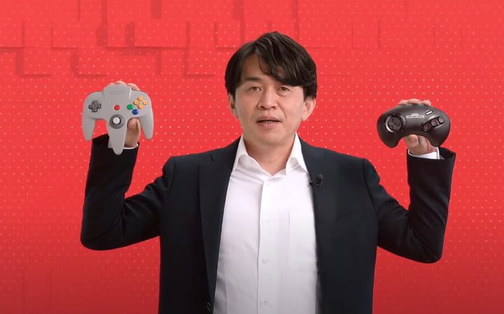 Ejecutvo de Nintendo mostrando en sus manos controladores N64 y Sega Genesis