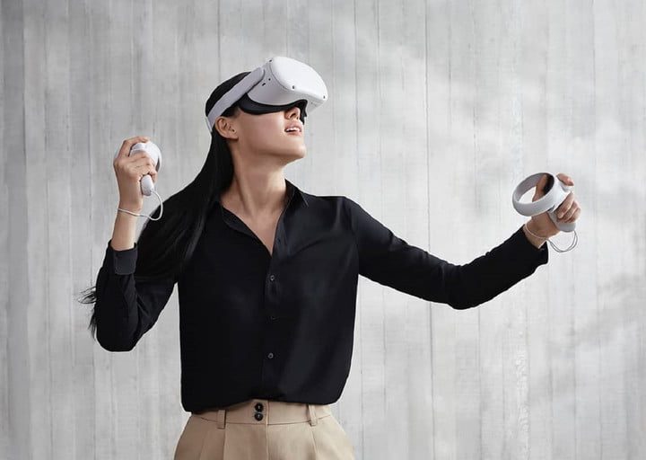 Una mujer que usa un visor de realidad virtual después de conectar Oculus Quest 2 frente a un fondo gris.