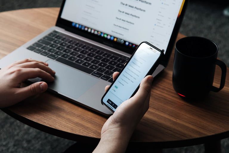 Una persona trabajando con su MacBook y un iPhone usando Handoff.