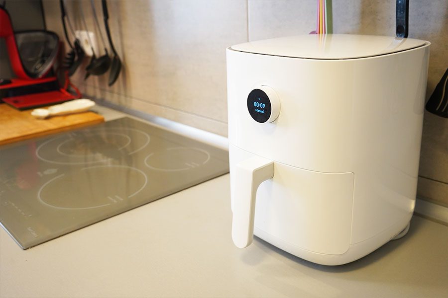 Freidora de aire de Xiaomi de color blanco en una cocina vista de lado. De fondo hay elementos de cocina.