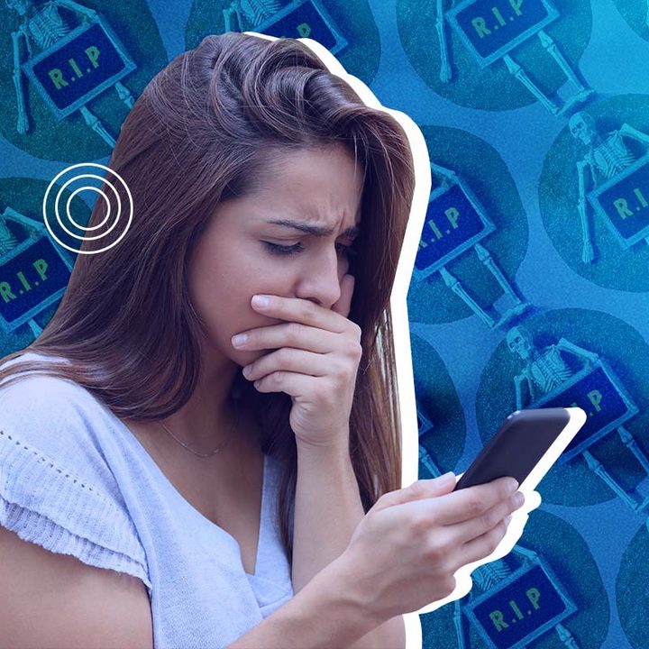 Mujer morena con el pelo largo mirando con cara de miedo y asombro a su teléfono móvil. De fondo hay varios esqueletos.